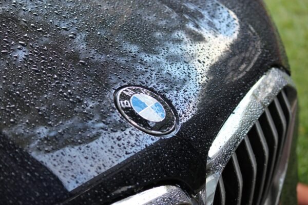 Rain-covered hood of a luxury car featuring a well-known logo.